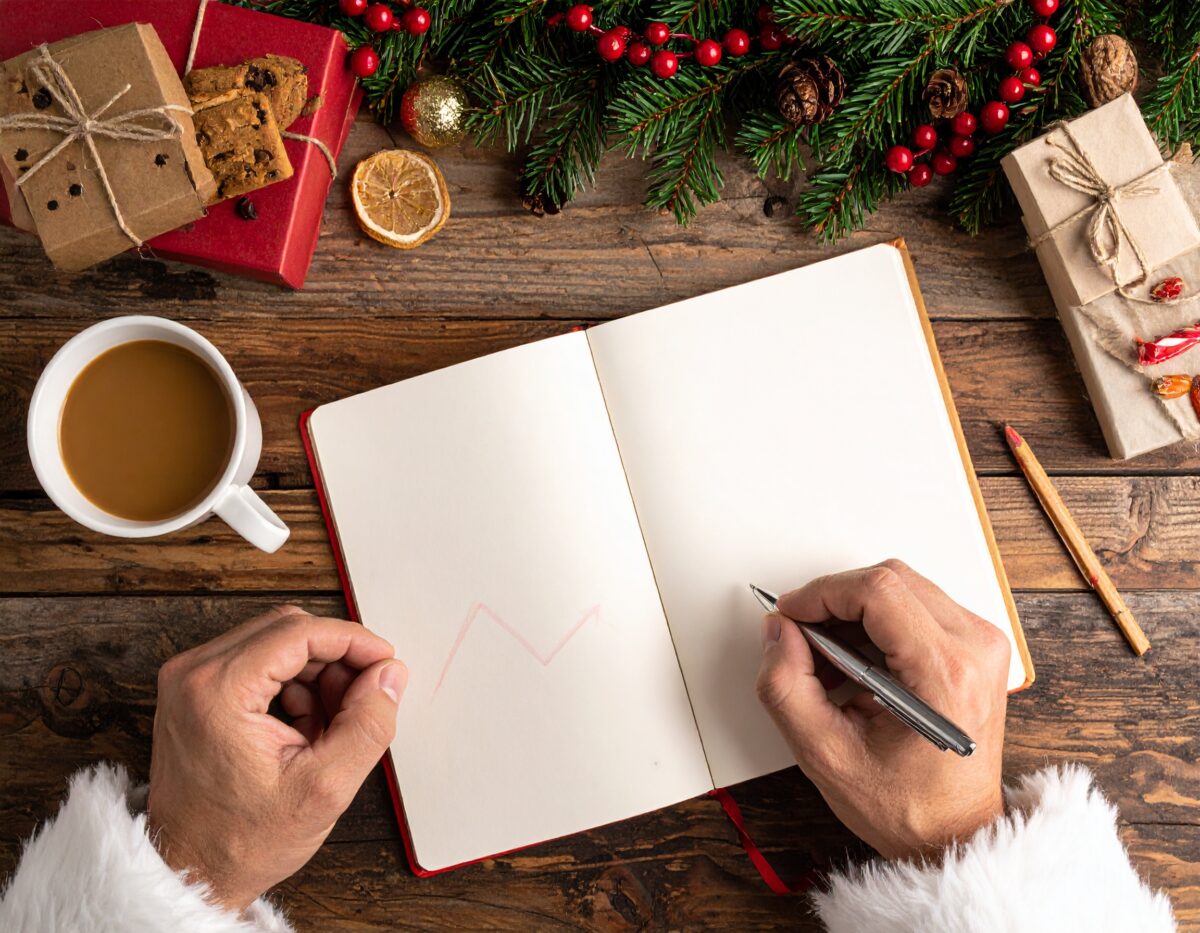 Santa hands holding a budget notebook with stock market arrows, symbolizing the Zero-Debt Christmas Challenge and the Dual Ascent for financial freedom