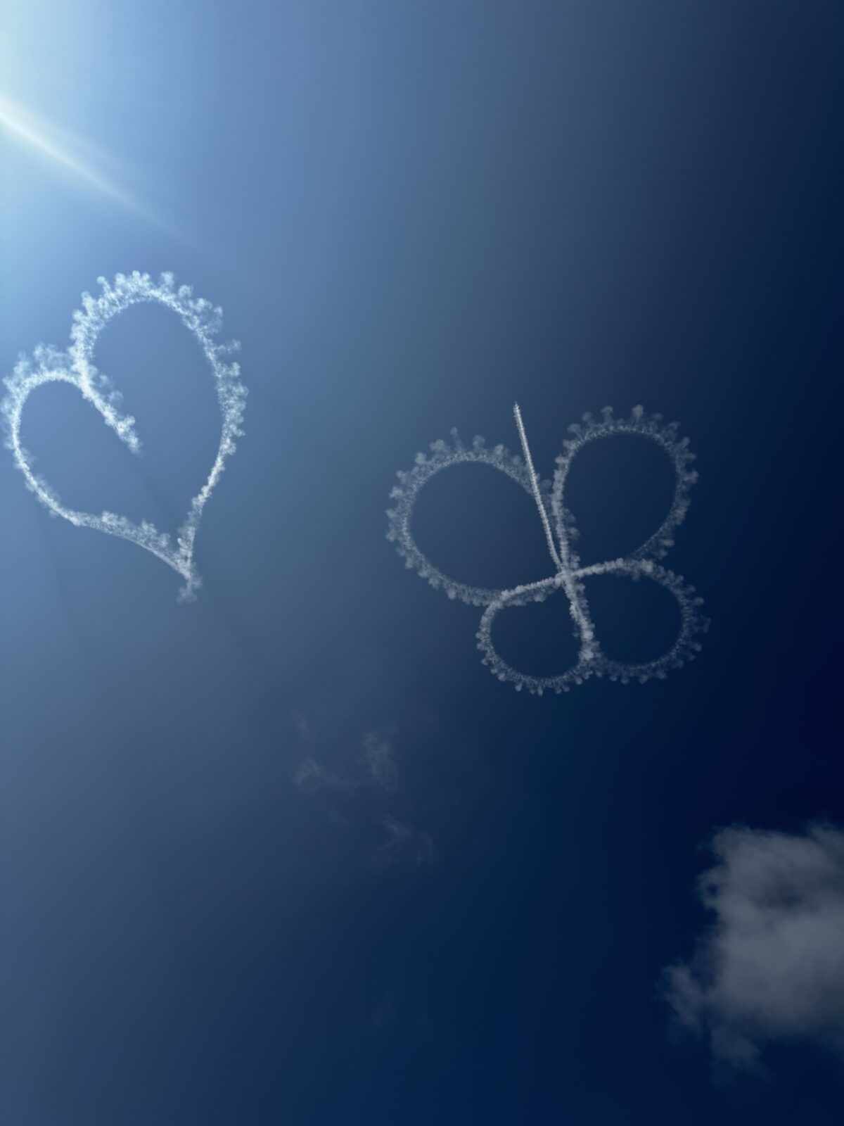 smoke ring trail forming a butterfly and heart shape at a summer airshow