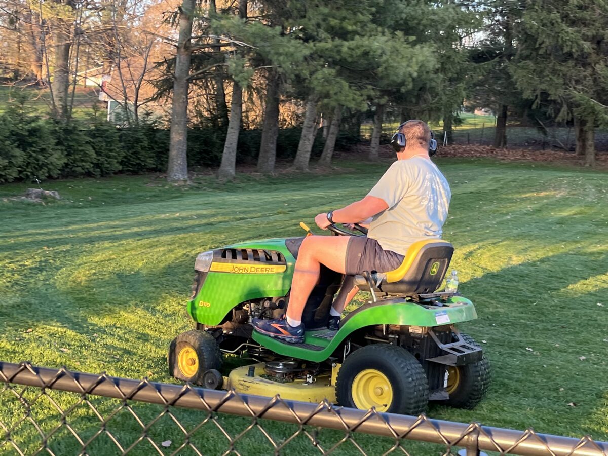 Teenager mowing lawn on a John Deere ride on mower earning money for chores